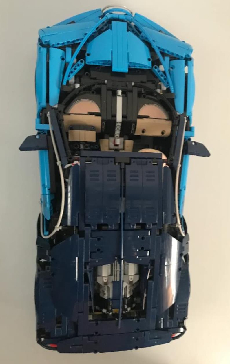 May include: A blue and dark blue Lego model car with the undercarriage exposed, showing the intricate details of the build.