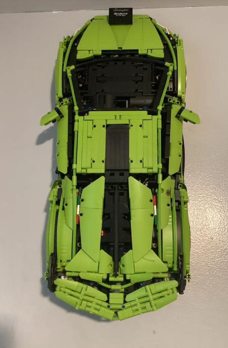 May include: A green Lamborghini Sian LEGO Technic model car with black details. The car is built with LEGO bricks and has a detailed engine and interior.