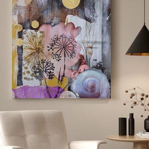 Könnte beinhalten: Abstrakter Kunstdruck mit einer Collage aus Texturen und Formen. Das Kunstwerk umfasst goldene Kreise, ein rosa Blumenelement und eine blaue Spiralform. Die Farbpalette umfasst Gold-, Rosa-, Lila- und Grautöne. Das Kunstwerk wird über einem weißen Sessel ausgestellt.
