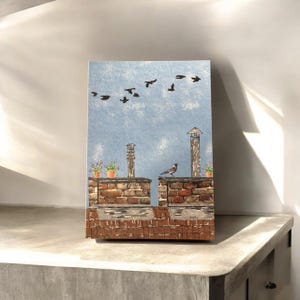 Può includere: Un dipinto che rappresenta un tetto di mattoni con due camini e un uccello appollaiato su uno di essi. Diversi uccelli volano nel cielo blu sopra.