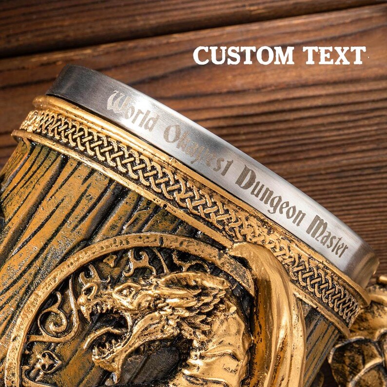 Op de afbeelding: Een decoratieve pul met een drakenontwerp. De pul is goud en bronskleurig met de tekst "World's Oldest Dungeon Master" gegraveerd op de rand. De woorden "Custom Text" zijn ook zichtbaar.