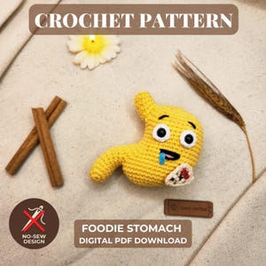 May include: A yellow crocheted stomach plushie with black eyes, a blue tongue, and a small taco graphic. The image includes text reading CROCHET PATTERN, FOODIE STOMACH DIGITAL PDF DOWNLOAD, and NO-SEW DESIGN, alongside cinnamon sticks and a flower.