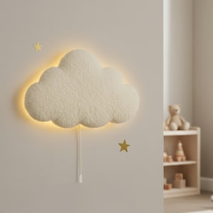 Könnte beinhalten: Eine cremefarbene, wolkenförmige Wandlampe mit warmem, gelbem Licht. Die Lampe hat eine weiche, strukturierte Oberfläche. Zwei goldene Sternaufkleber sind an der Wand angebracht. Die Lampe ist an eine Steckdose angeschlossen.
