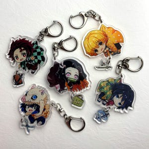 Op de afbeelding: Een verzameling acryl sleutelhangers met anime-personages. Elke sleutelhanger heeft een zilverkleurige sluiting en toont een ander personage in levendige kleuren. De sleutelhangers zijn ontworpen met gedetailleerde illustraties en zijn geschikt voor fans van de animeserie.