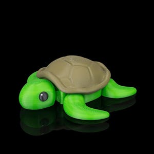Puede incluir: Figura de tortuga impresa en 3D, con cuerpo verde y caparazón marrón. La tortuga tiene un patrón de caparazón detallado, un ojo negro y está posada sobre una superficie negra reflectante. Un artículo decorativo caprichoso.