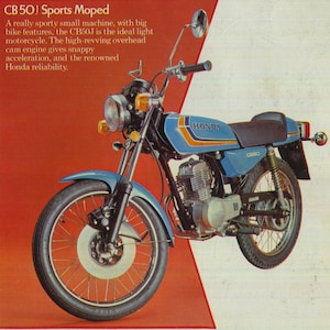 Puede incluir: Una motocicleta Honda CB50J azul y naranja con un motor de leva en cabeza de alta revolución. La motocicleta tiene un asiento negro, un manillar cromado y un tubo de escape cromado.