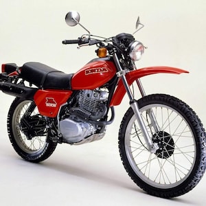 May include: A red Honda XR 500R motorcycle with a black seat and black tyres. The motorcycle has a silver headlight and a silver rearview mirror.