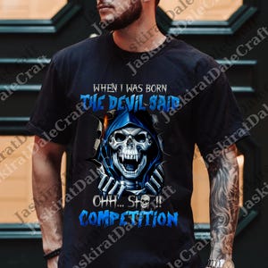 Könnte beinhalten: Schwarzes T-Shirt mit einem Totenkopf-Motiv mit blauem Kapuzenmantel und dem Text "WHEN I WAS BORN THE DEVIL SAID OHH... SH*T!! COMPETITION". Das Design beinhaltet einen Totenkopf mit offenem Mund und Skeletthänden.
