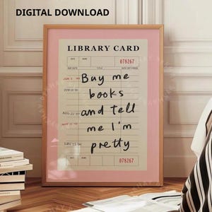 Könnte beinhalten: Ein gerahmter Druck mit einem rosa Rand, der ein Vintage-Bibliothekskartendesign zeigt. Die Karte hat handgeschriebenen Text, der lautet: "Buy me books and tell me I'm pretty". Die Worte "DIGITAL DOWNLOAD" stehen oben.