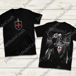 May include: Black t-shirts featuring Crusader-themed designs. One shirt displays a shield with a red cross and sword. The other shirt shows a Crusader on horseback with a red cross, surrounded by soldiers and text.