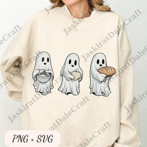 May include: A cream-coloured sweatshirt with a design of three cartoon ghosts. Each ghost is holding an item: a bowl, a loaf of bread, and a round object. The text "PNG + SVG" is at the bottom.