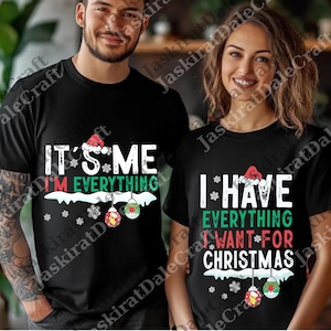 以下が含まれることがあります： クリスマスをテーマにしたテキストがプリントされた黒いTシャツ。片方のシャツには「IT'S ME I'M EVERYTHING」とサンタの帽子とオーナメントのグラフィックが描かれています。もう一方のシャツには「I HAVE EVERYTHING I WANT FOR CHRISTMAS」と書かれています。