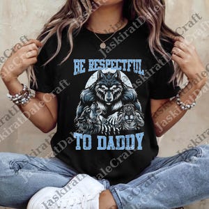 May include: Black t-shirt featuring a wolf design with the text "BE RESPECTFUL TO DADDY" in light blue. The graphic includes a large wolf and two smaller wolves, creating a bold and eye-catching design.