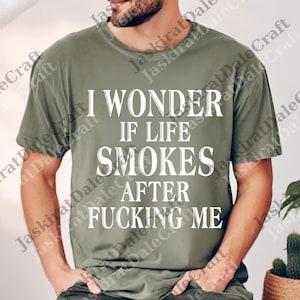 May include: Olive green t-shirt with the white text "I WONDER IF LIFE SMOKES AFTER FUCKING ME". The shirt is a casual style, with a relaxed fit. The text is centered on the front.
