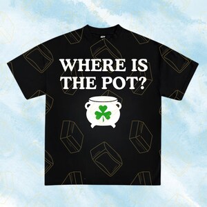 May include: Black t-shirt with the text "WHERE IS THE POT?" in white. A white pot with a green shamrock is centered below the text. The shirt has a repeating pattern of gold-colored boxes.