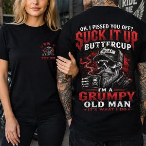 May include: A black t-shirt featuring a graphic on the back of a bearded skull wearing a cap and sunglasses, holding a mug with a skull and crossbones. The text reads: OH, I PISSED YOU OFF? SUCK IT UP BUTTERCUP, IDGAF, I'M A GRUMPY OLD MAN, IT'S WHAT I DO.