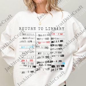 May include: White sweatshirt with a black and red graphic that resembles a library card. The graphic reads "RETURN TO LIBRARY" with various dates listed below. A casual, comfortable top.