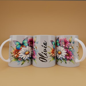 Puede incluir: Tres tazas de cerámica blanca con un diseño floral con mariposas y el nombre "Olivia" impreso en la taza del medio.