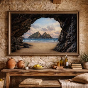 May include: A framed landscape painting depicts a coastal scene viewed from a cave opening. The artwork showcases a sandy beach, ocean, and distant mountains under a cloudy sky. The painting is displayed above a wooden table with pottery, fruit, and decorative items.