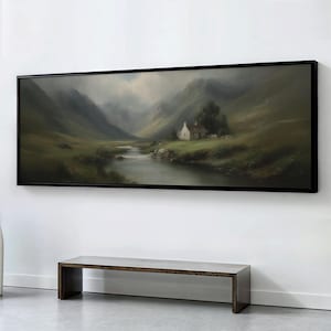 May include: A framed landscape painting showing a tranquil valley with a river, mountains, and a small white cottage. The artwork is in a black frame and hangs above a wooden bench. The color scheme includes muted greens, browns, and greys.