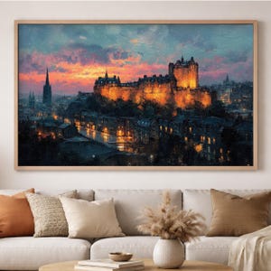 Puede incluir: Pintura enmarcada de un paisaje urbano con un castillo iluminado al atardecer. Los colores cálidos anaranjados y amarillos del castillo contrastan con los azules y morados del cielo y los edificios. El cuadro está colgado sobre un sofá.