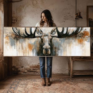 Pode incluir: Uma impressão de arte de parede retangular e larga com uma pintura detalhada de uma cabeça de alce com chifres grandes e escuros. A obra usa uma paleta de cinzas, marrons e brancos suaves, com pinceladas e gotas de tinta visíveis.