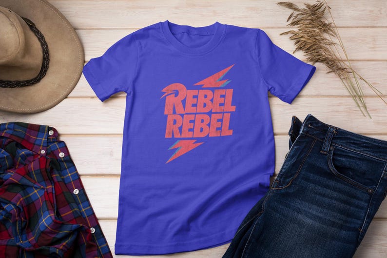 May include: A royal blue t-shirt with a red lightning bolt graphic and the text "Rebel Rebel" printed on the front.