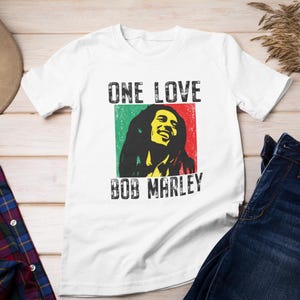 May include: White t-shirt with a graphic of Bob Marley and the text "One Love Bob Marley".
