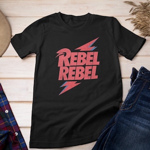 May include: Black t-shirt with a red and blue graphic print of the words "Rebel Rebel" with a lightning bolt design.