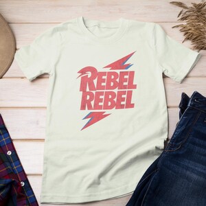May include: A white t-shirt with a red and blue graphic design that says "Rebel Rebel".