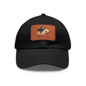 May include: Black baseball cap with a brown leather patch featuring a cartoon cat riding a worm with the text "Meow'Dib".