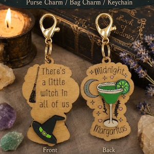 May include: Double-sided wooden purse charm with gold clasp. One side reads "There's a little witch in all of us" with a witch hat and broom. The other side says "Midnight Margaritas" with a green cocktail.