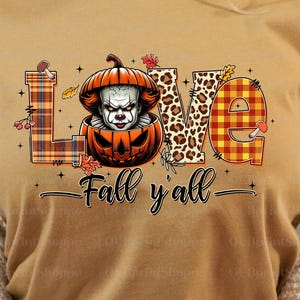 May include: Mustard-coloured t-shirt with a graphic design featuring the word "LOVE" in various patterns, including plaid and leopard print. A pumpkin with a scary face is in the centre. The text "Fall y'all" is below the word "LOVE".