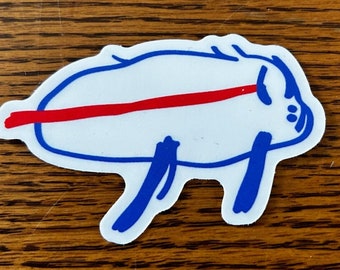May include: A white sticker with a blue outline of a pig with a red line across its body. The pig has a blue snout and blue legs.