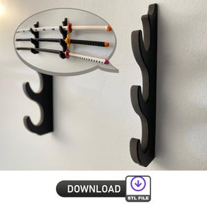 Könnte beinhalten: Schwarzer Wand-Schwertständer mit drei gebogenen Schlitzen. Das Bild zeigt drei Schwerter mit weißen, schwarzen und gemusterten Griffen. Die Schwerter werden an einer weißen Wand ausgestellt. Das Bild enthält auch eine "DOWNLOAD"-Schaltfläche mit einem "STL FILE"-Symbol.