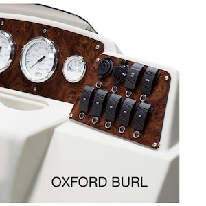 Puede incluir: Primer plano del tablero de un barco con acabado de madera. El tablero presenta una variedad de indicadores y interruptores, incluyendo un veloc&iacute;metro, un tac&oacute;metro y un volt&iacute;metro. El texto "OXFORD BURL" est&aacute; impreso en el tablero.