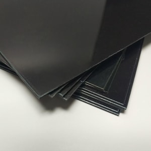 May include: A stack of black, glossy, rectangular sheets of paper.