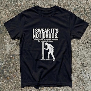 May include: Black t-shirt with white text: "I SWEAR IT'S NOT DRUGS." The text below reads: "I'm just feeling up a public lamppost for a magnetic nano." A white graphic shows a person interacting with a lamppost.