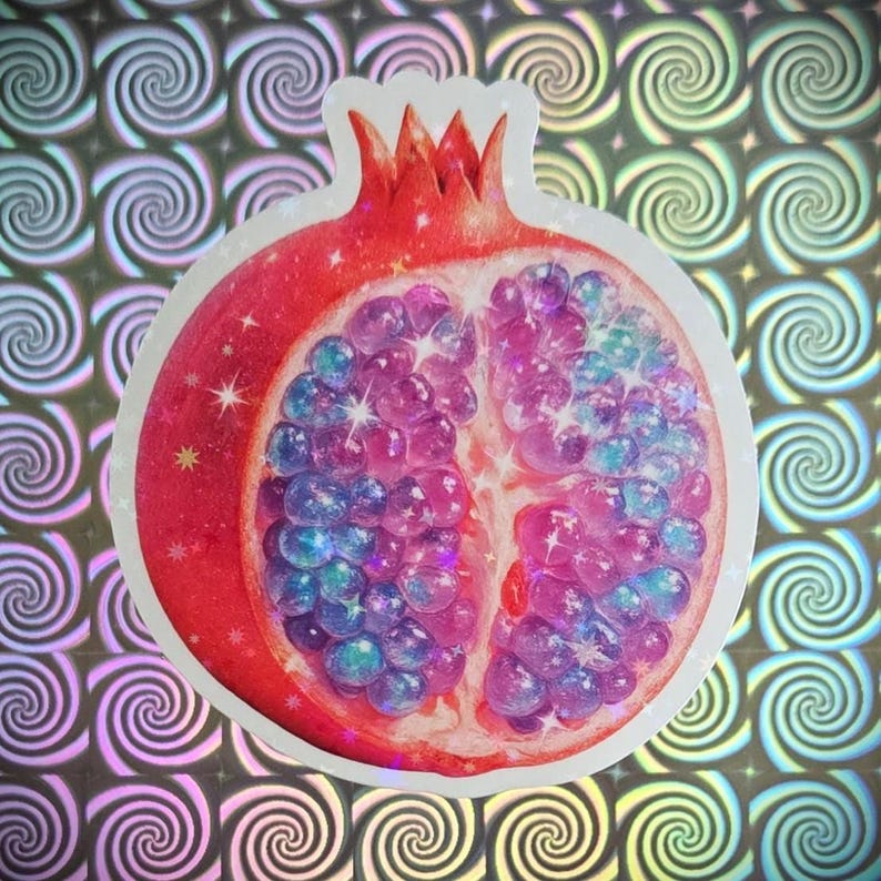 May include: A sticker featuring a stylized pomegranate cut in half, showcasing vibrant pink, purple, and blue seeds. The red rind is detailed with sparkles. The background is a holographic pattern of swirling shapes.