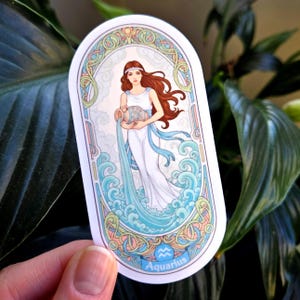 Pu&ograve; includere: Un adesivo ovale con un'illustrazione del segno zodiacale dell'Acquario. Una donna in abito bianco versa acqua da un vaso. Il design include colori blu, turchese e pastello con la parola "Aquarius" in basso.