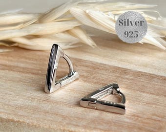 Peut inclure: Une paire de boucles d'oreilles créoles triangulaires en argent. Les boucles d'oreilles sont en métal poli et présentent un design géométrique. L'image comprend un cercle argenté avec le texte "Silver 925".