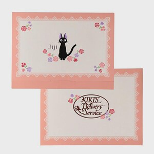 May include: Two pink envelopes with a white interior and a lace border. The top envelope features a black cat named Jiji surrounded by flowers. The bottom envelope has the text "KIKIS Delivery Service" with a witch on a broom.