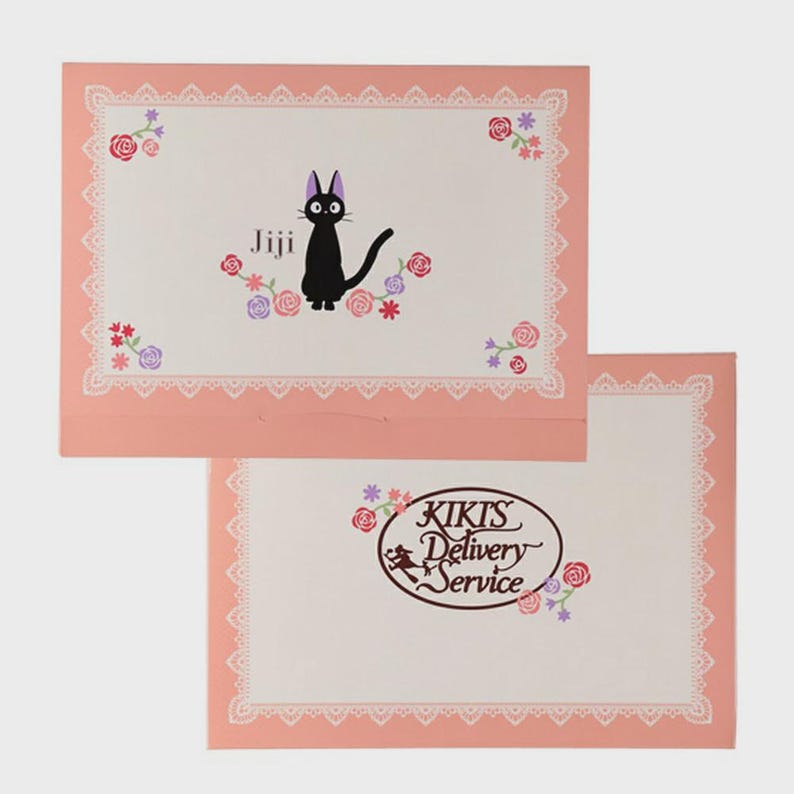 May include: Two pink envelopes with a white interior and a lace border. The top envelope features a black cat named Jiji surrounded by flowers. The bottom envelope has the text "KIKIS Delivery Service" with a witch on a broom.