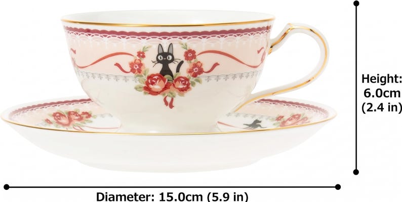 May include: A cream-colored teacup and saucer set with a black cat illustration and floral accents. The cup is 2.4 inches tall and the saucer is 5.9 inches in diameter. Gold trim edges the cup and saucer.