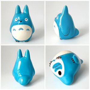 May include: A blue ceramic figurine of Totoro, a character from the animated film My Neighbor Totoro. The figurine has large ears, a white belly, and brown feet. The bottom of the figurine has the text "Studio Ghibli Sousei".