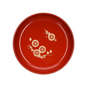 May include: A round, red serving tray with a glossy finish. The tray features a decorative pattern of stylized wheels, flowers, and small rabbit figures in a cream color. The design is arranged across the surface of the tray.