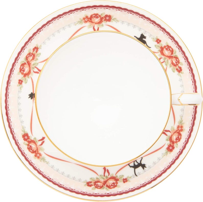 May include: A white ceramic ashtray with a floral rose design in red and peach, accented with gold trim. The rim features a scalloped edge and a decorative ribbon pattern. Two black cat silhouettes are also featured.