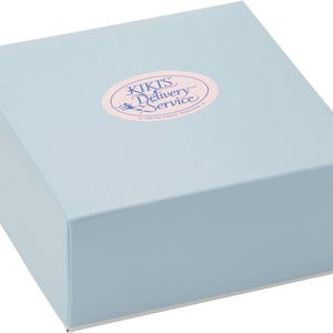 May include: A light blue square box with a matching lid. An oval sticker on the lid reads "KIKI'S Delivery Service" in pink and white text. The box is likely for packaging or gifting.