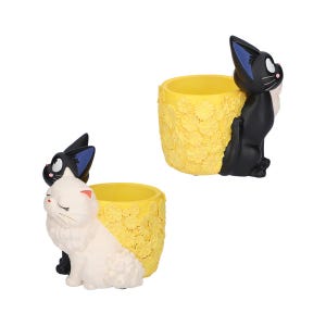 Puede incluir: Dos macetas cil&iacute;ndricas con exterior amarillo y un patr&oacute;n floral texturizado. Una maceta presenta un gato negro con orejas bordeadas en azul, mientras que la otra tiene un gato blanco con ojos cerrados y orejas con puntas rosadas.