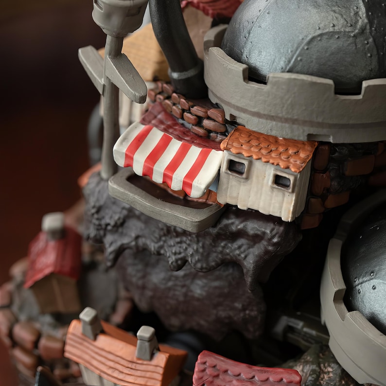 May include: A detailed miniature castle model with a gray, domed turret and a red and white striped awning. The model features small, detailed buildings with brown and red roofs, and a textured, rocky base.
